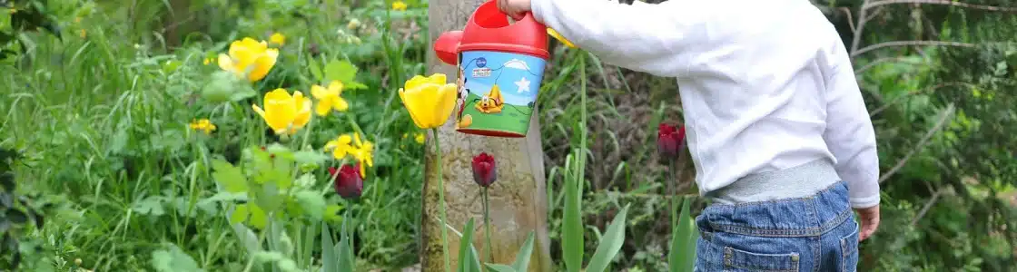 Kind spielt im Garten mit Kindergießkanne