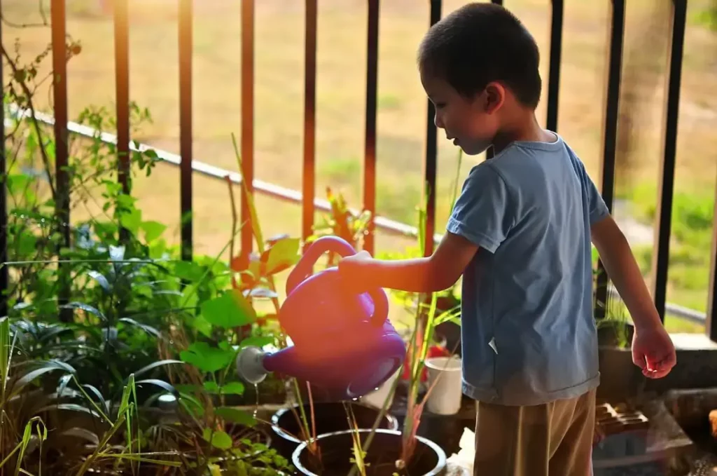 kleiner Junge gießt Topfpflanzen