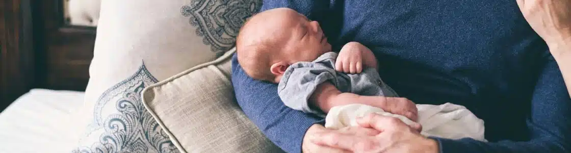 Erwachsener hält Neugeborenes im Arm